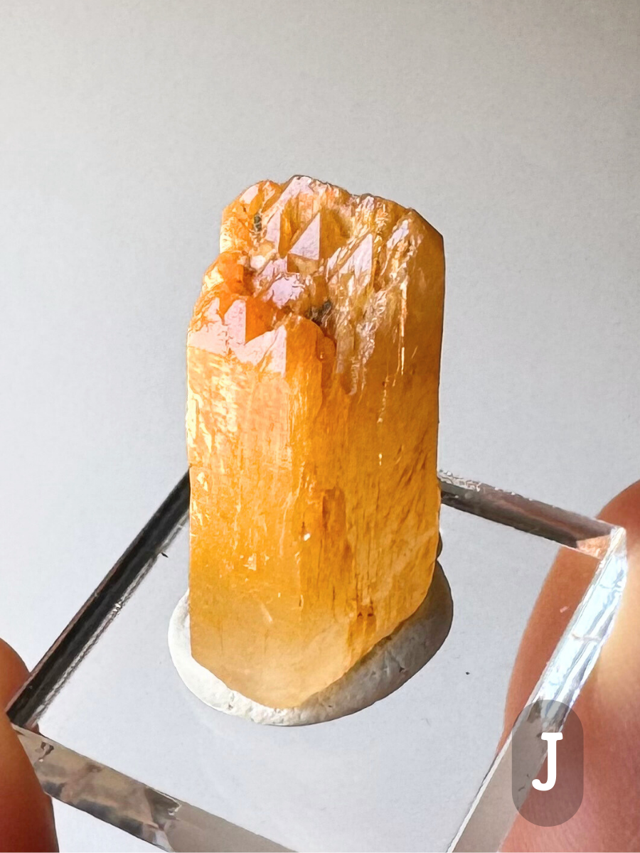 Option J, a long wide point with more classic corona termination, forming a half dozen small triangular tip faces up a slanted face. The piece is heavily included with halloysite, a deep yellow-orange at the tips and saturated orange-yellow throughout.