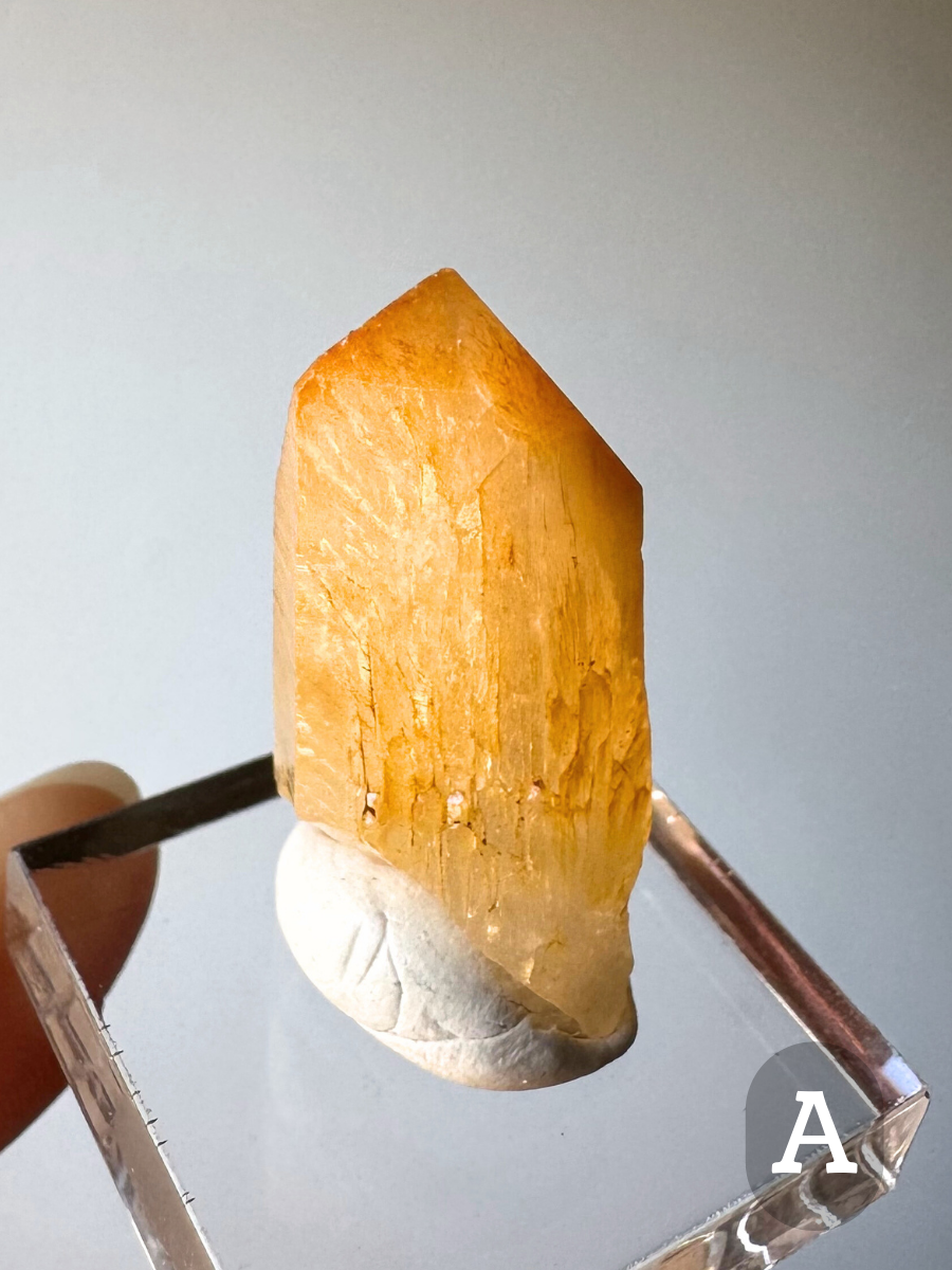 Option A, a short wide quartz point heavily included with halloysite throughout, the tip a deeper yellow-orange and the body of the point vibrant golden. There are sprouting growth forms on the crystal faces.