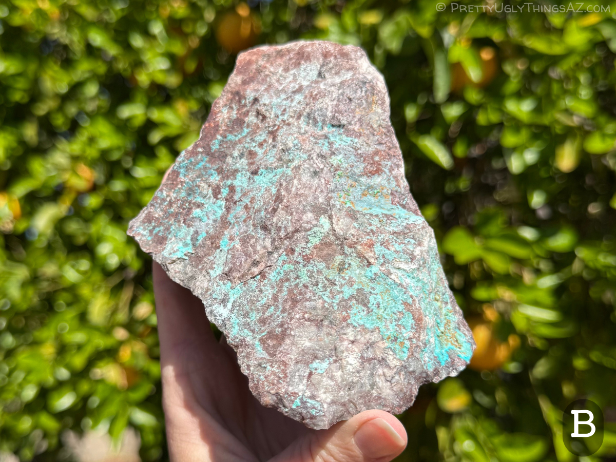 Option B, a flattish but wide roughly rectangular piece of rough, the surface dark red-brown with iron oxides. Brilliant blue contrasts with this, with some patches of small green crystals with orange rusty staining around them.