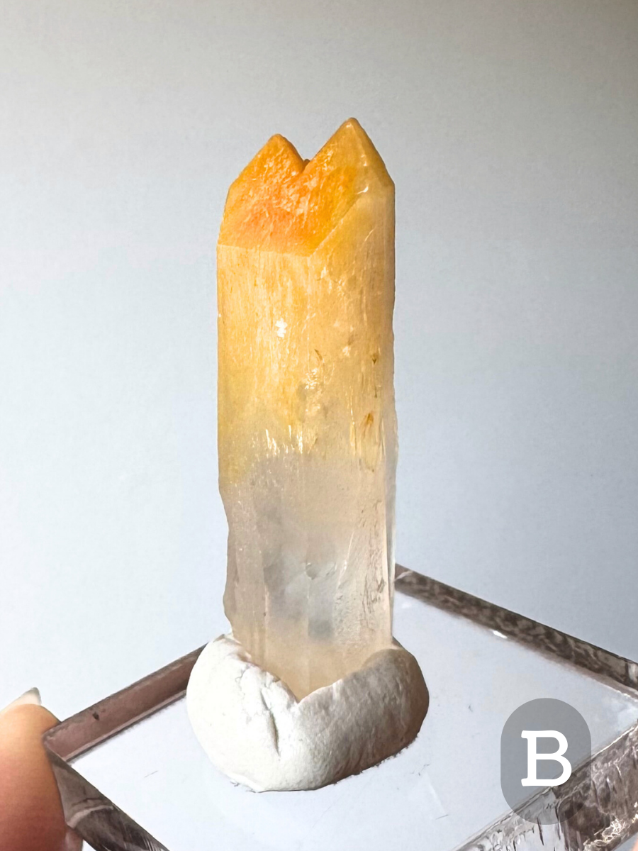Option B, a point that is long and narrow, the point split into two main tips. The tips are saturated orange-yellow, fading in a gradient to gold then a clear slightly milky colorless base.