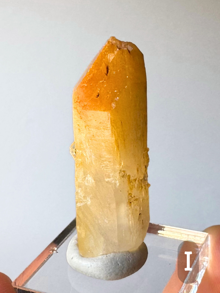 Option I, a long thick point heavily included with halloysite, yellow-orange with an asymmetic tip, color fading to light golden yellow and semi-translucent at the base