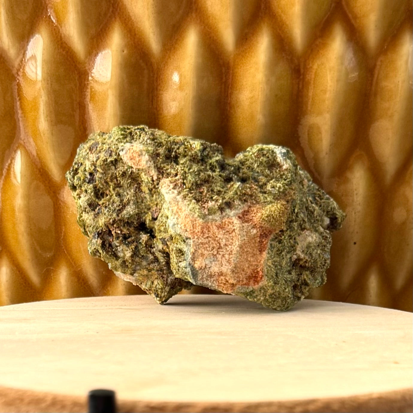 Full view of the back of the specimen, rough green epidote aggregate with a patch of light brown matrix in the center.