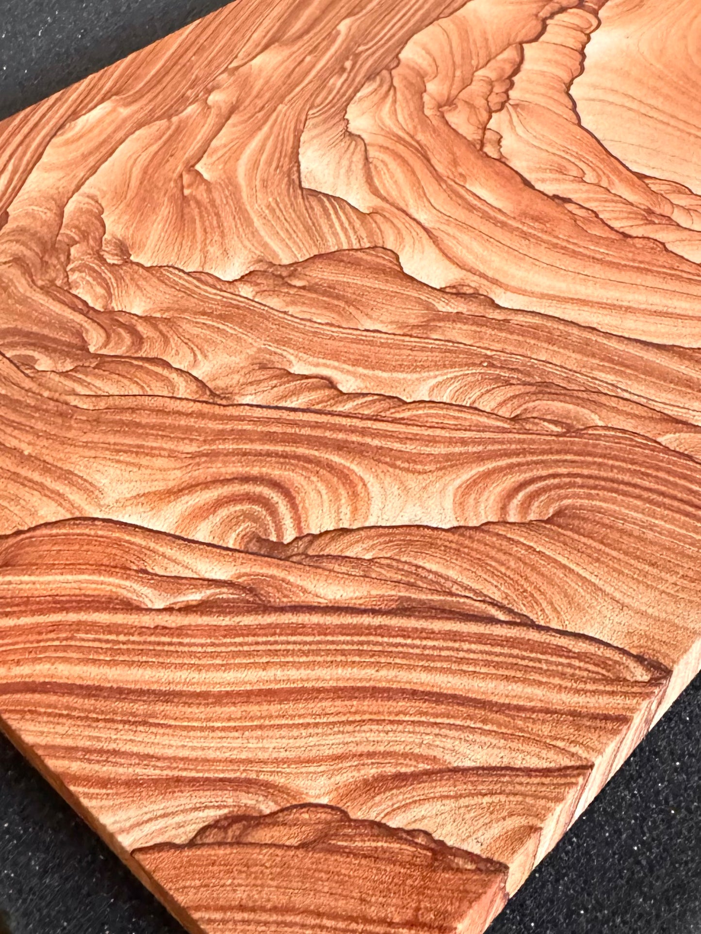 Angled view looking across the slab from the bottom right corner, emphasizing high-contrast layering that begins in that corner. Near the center of the image is a loop-like form of layers.