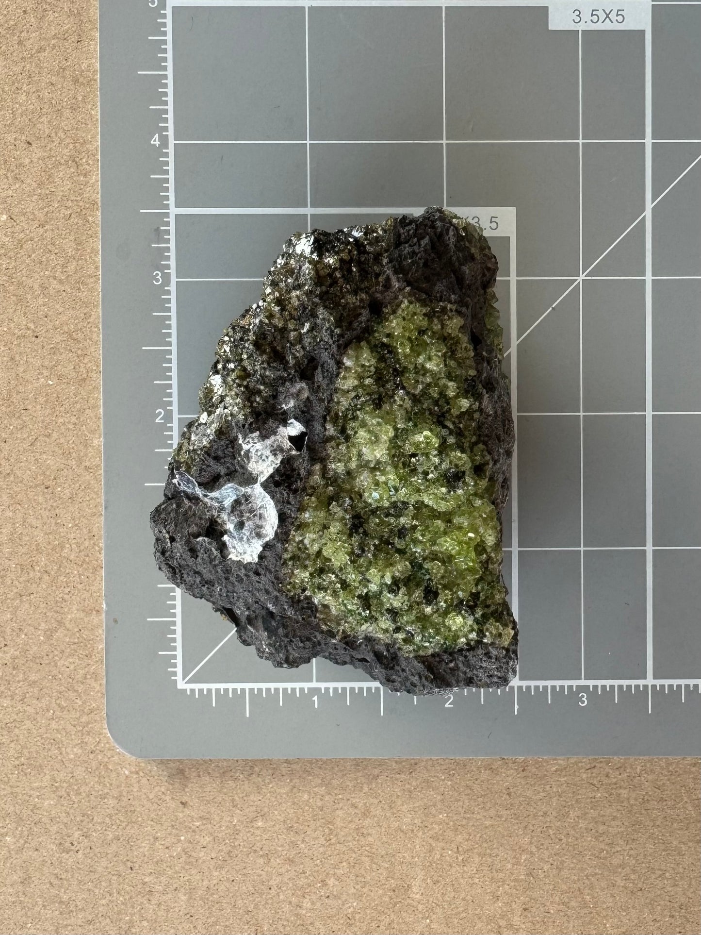 Scale image of the piece on a measuring mat, measuring almost three inches long and two inches wide