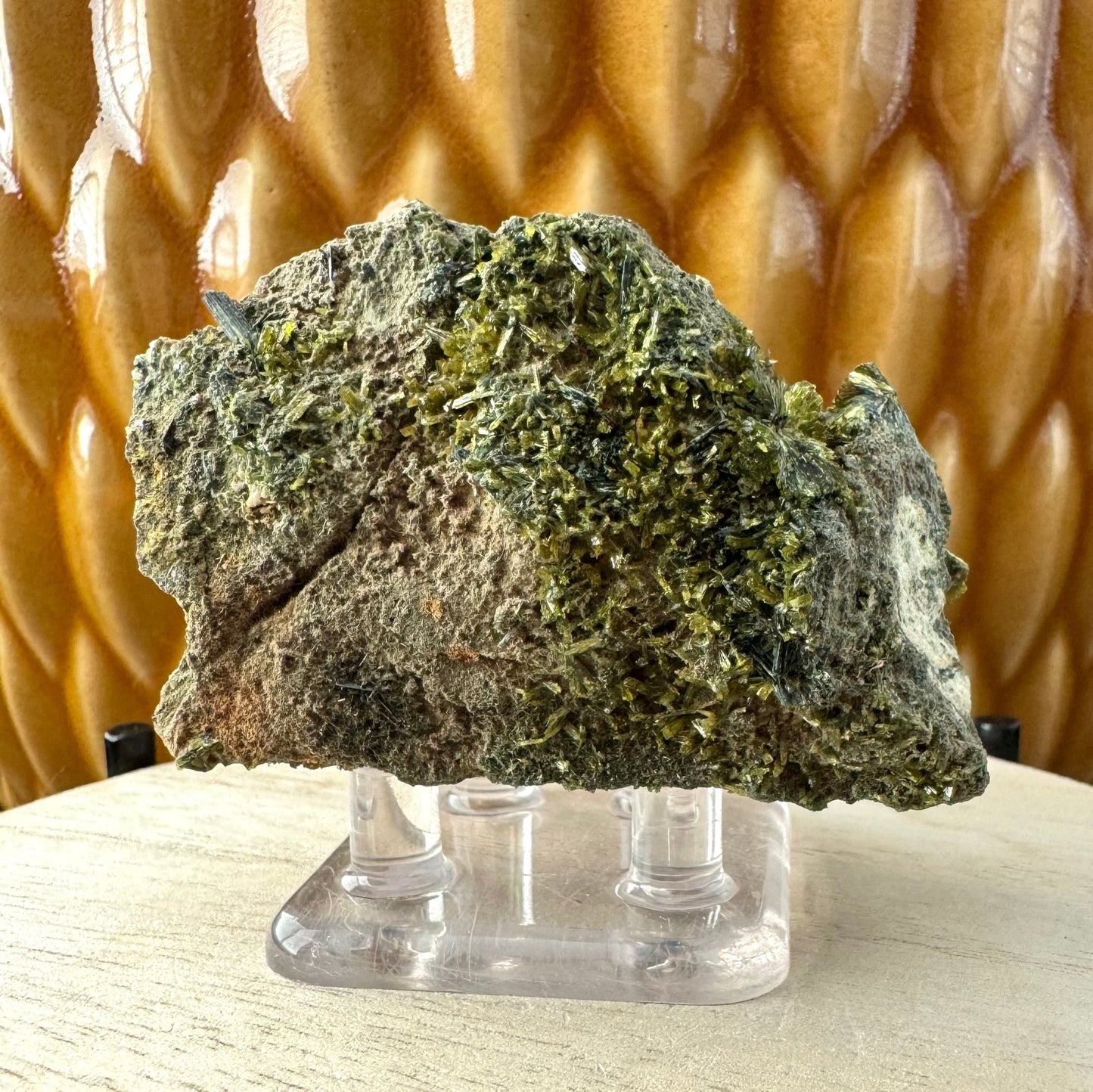 The front of a rectangular piece of matrix covered with epidote crystals, light and darker green with some finer near-black crystals.