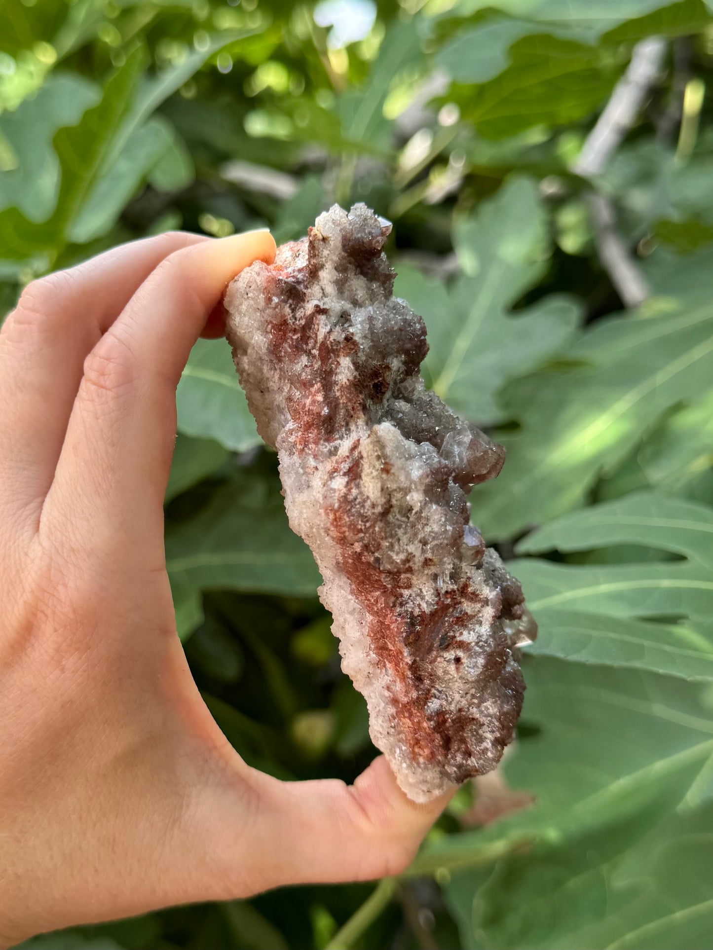Side view of the piece, showing the druzy is atop a layer of mixed white and dark red matrix, with a white base.
