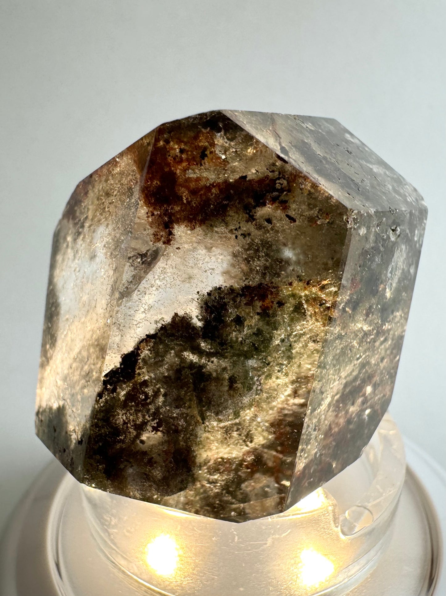 The piece illuminated from below, with the internal light greenish and copper-brown inclusions are illuminated