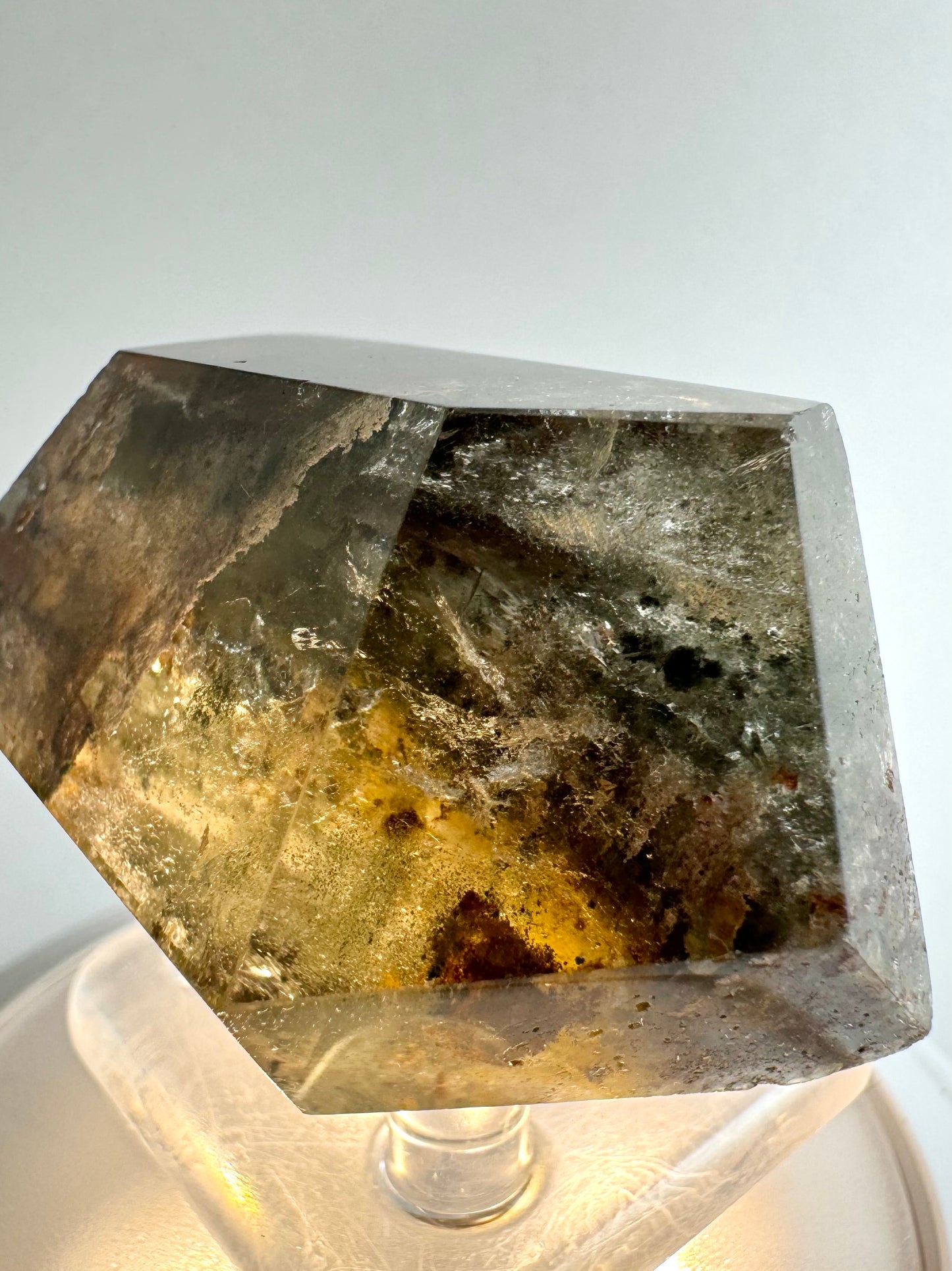 The piece of garden quartz illuminated from beneath by a light, highlighting wispy colorless inclusions