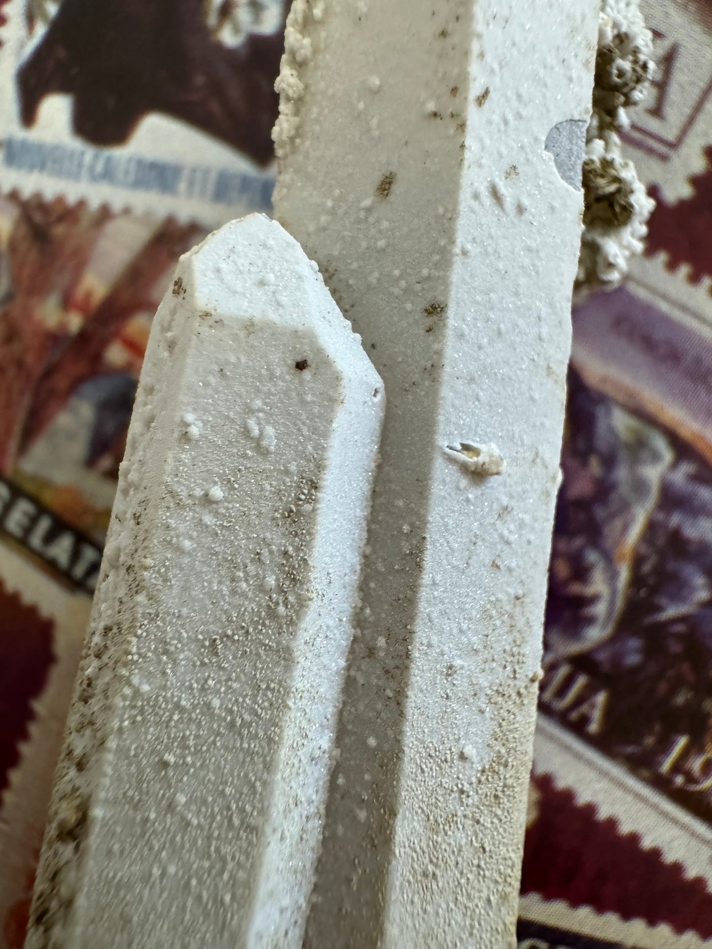 Detail of the tip of the shorter point and the surface of the white crust, a grainy texture with some larger white spheres on the surface.