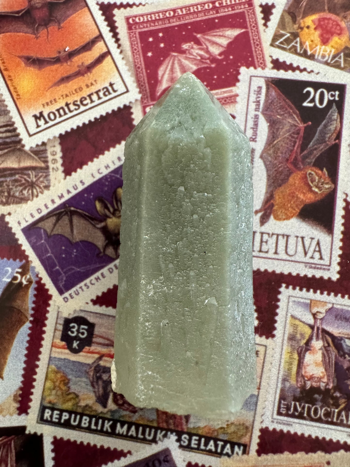 The point in indirect light, without reflection. It seems to have a dull surface luster, with a light green-gray body color. The piece is semi-translucent. The complex surface pattern of the sprouting growth is subtle but visible.