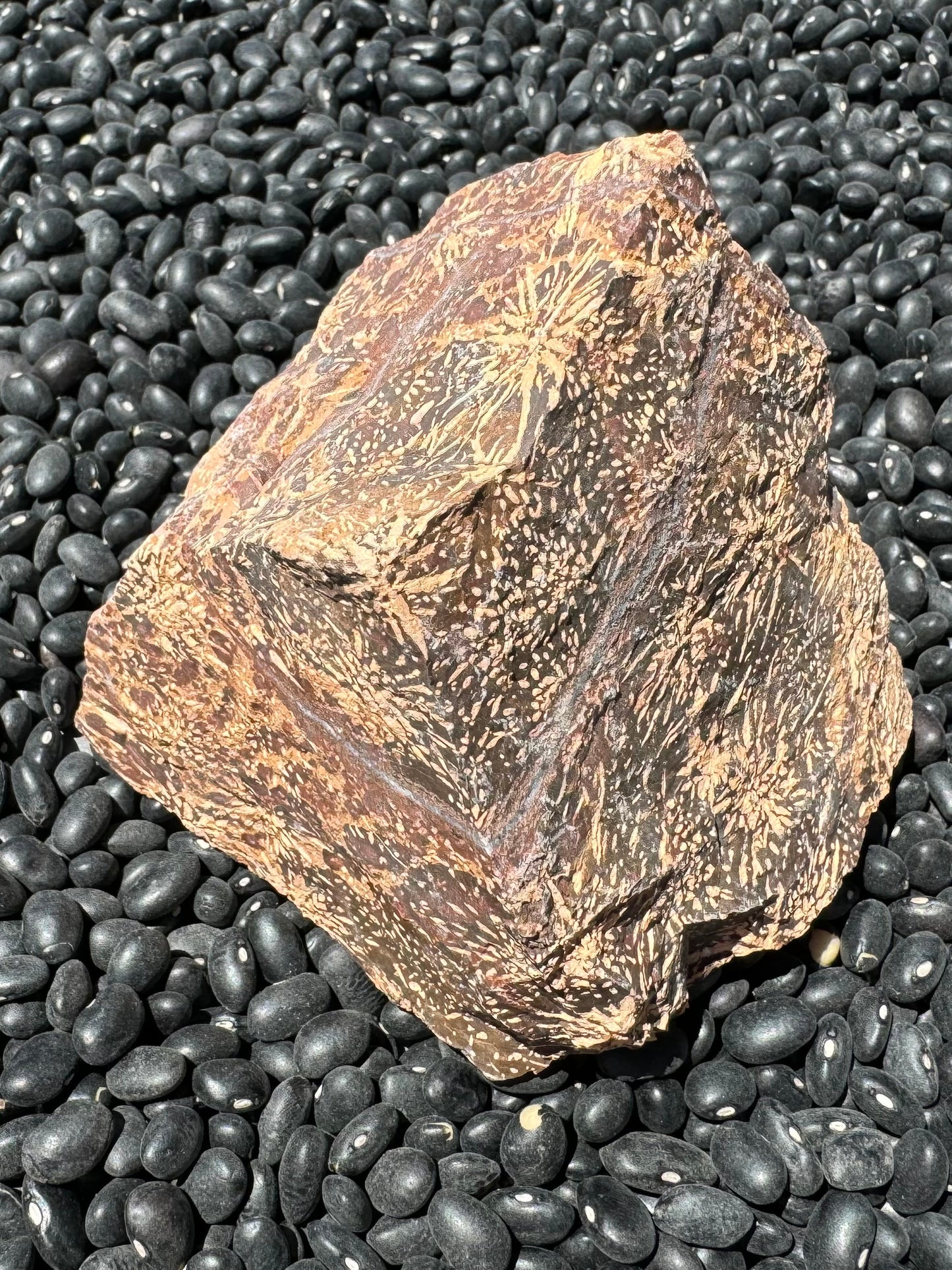 Looking down at the piece, a triangular face and two sides visible coming to a point. A white quartz vein can be seen on all sides, ringing the top.