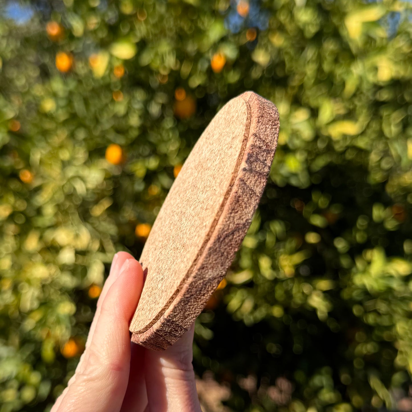 A coaster held sideways to show it is a relatively thin slab of sandstone