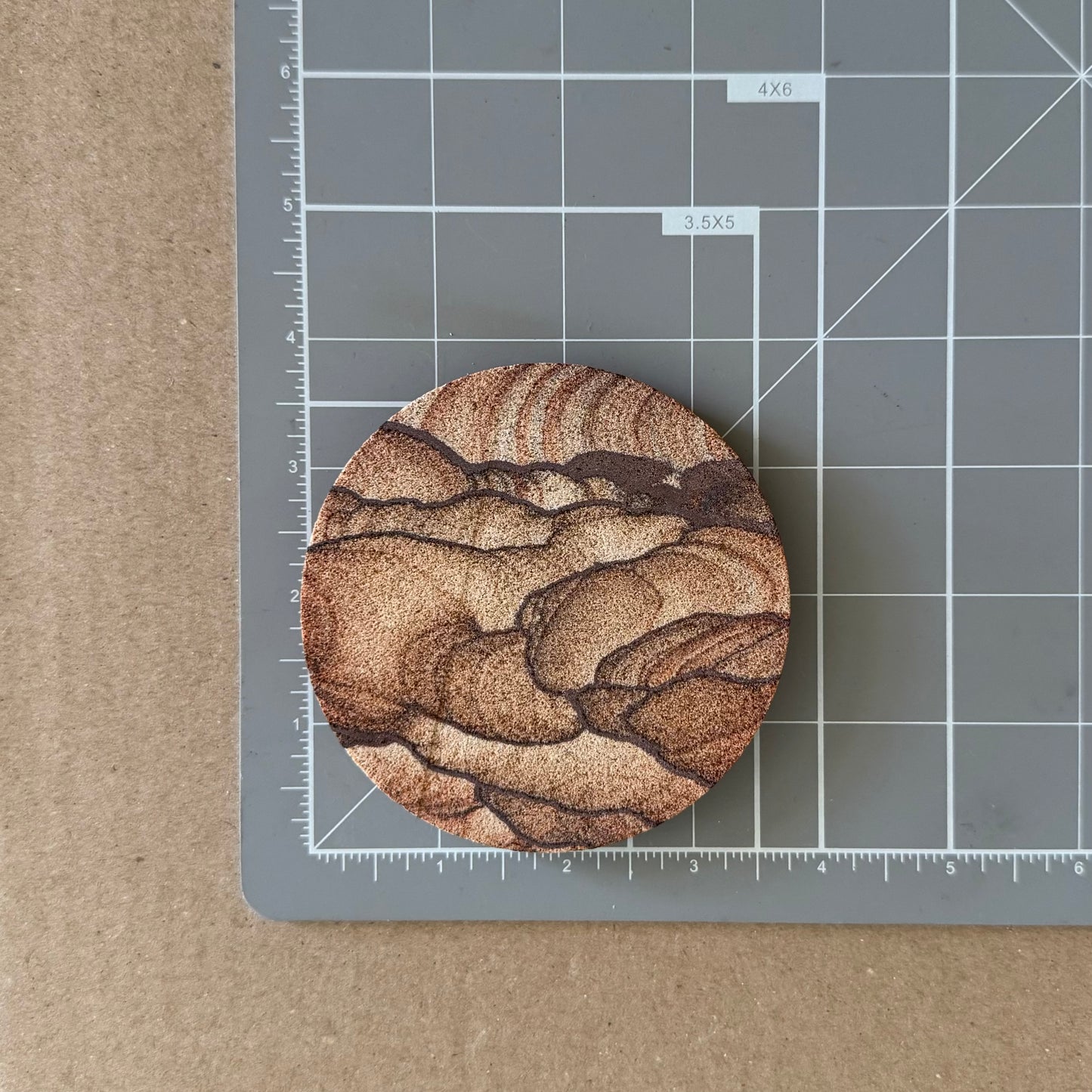 A coaster on a measuring mat, showing it measures a bit under four inches in diameter.