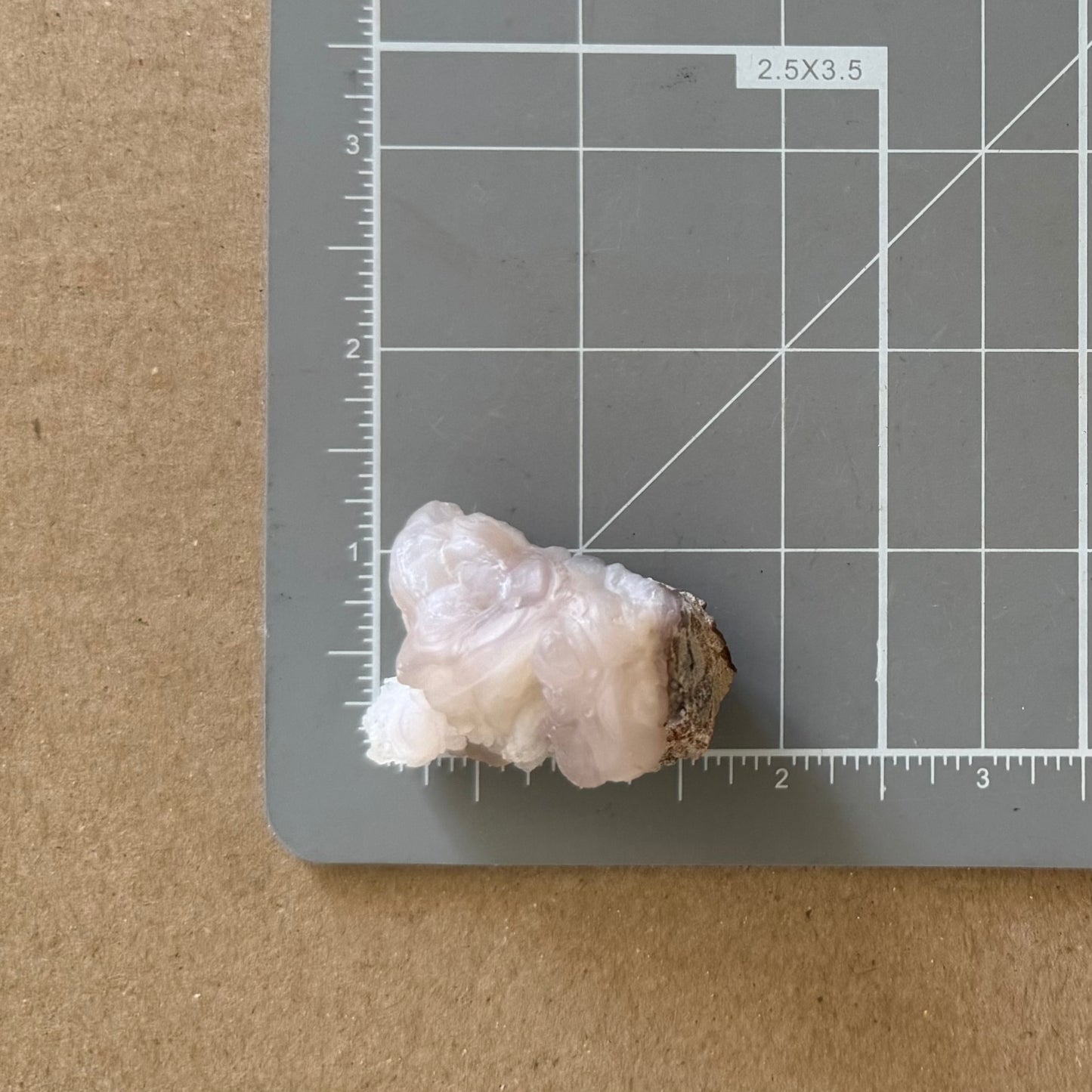 The piece on a measuring mat, measuring about an inch and a half long and an inch wide.