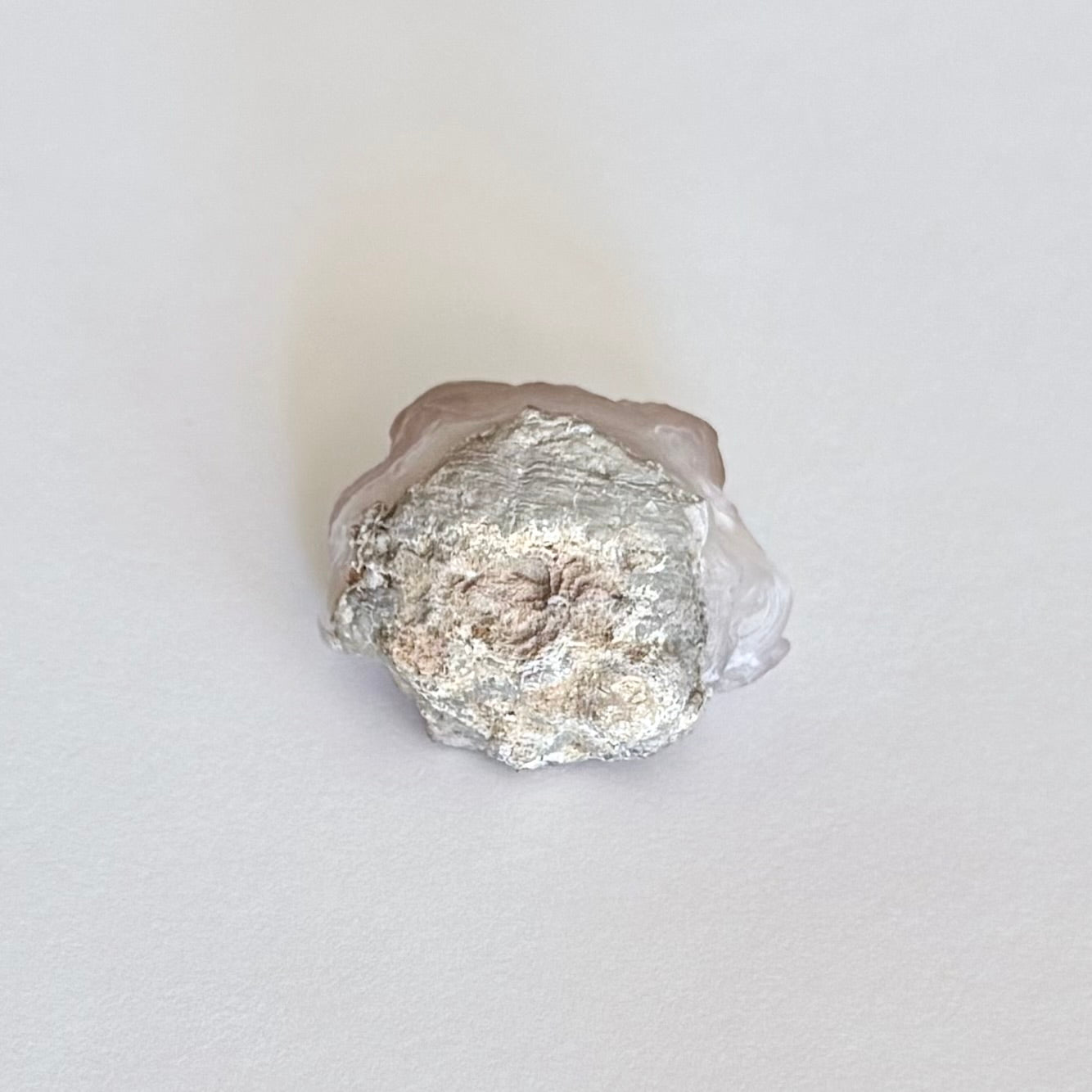 The underside of the piece, a rounded broken light gray rock matrix.