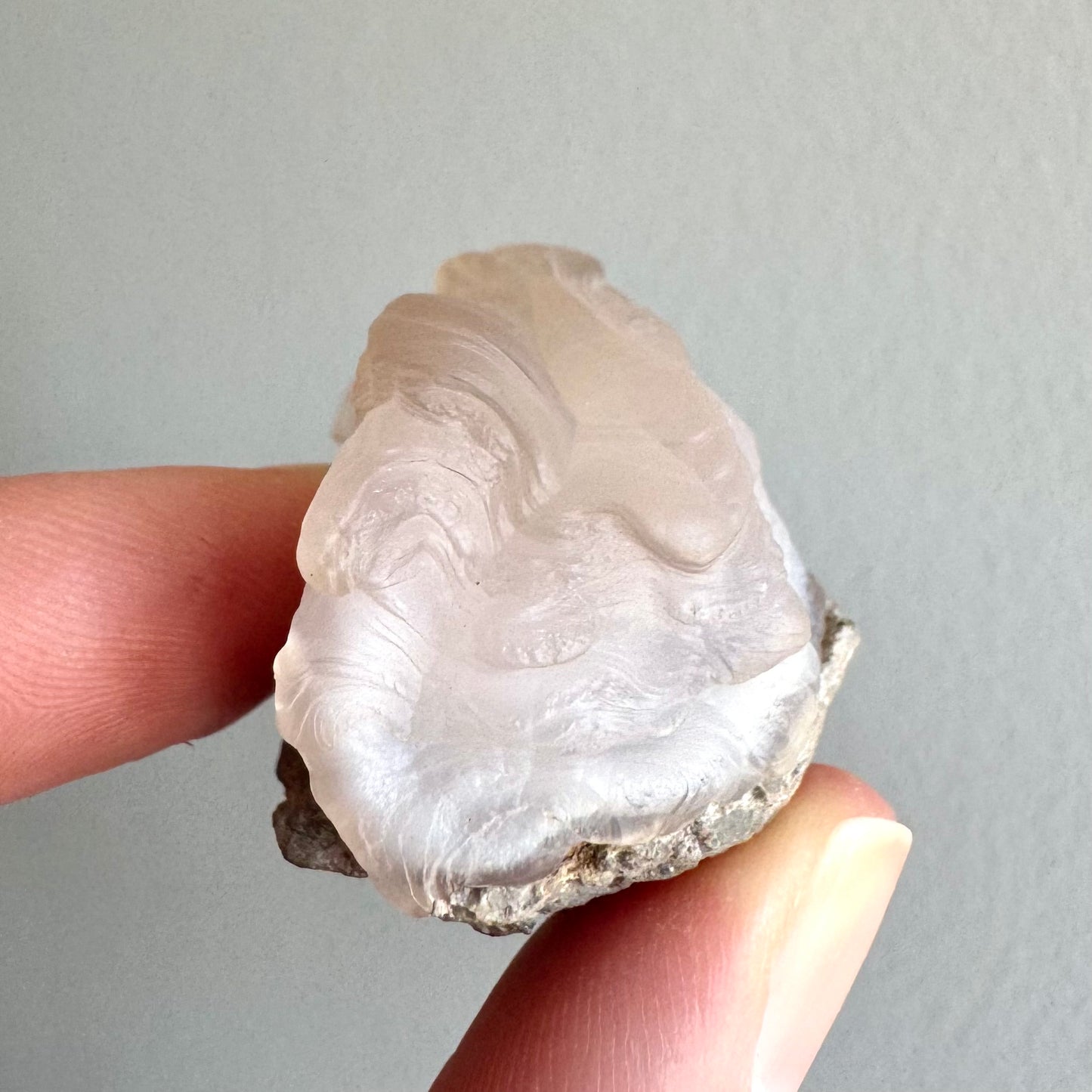 End-view of the piece, showing the undulating layering, more pink-tinted and the top and white in the center.
