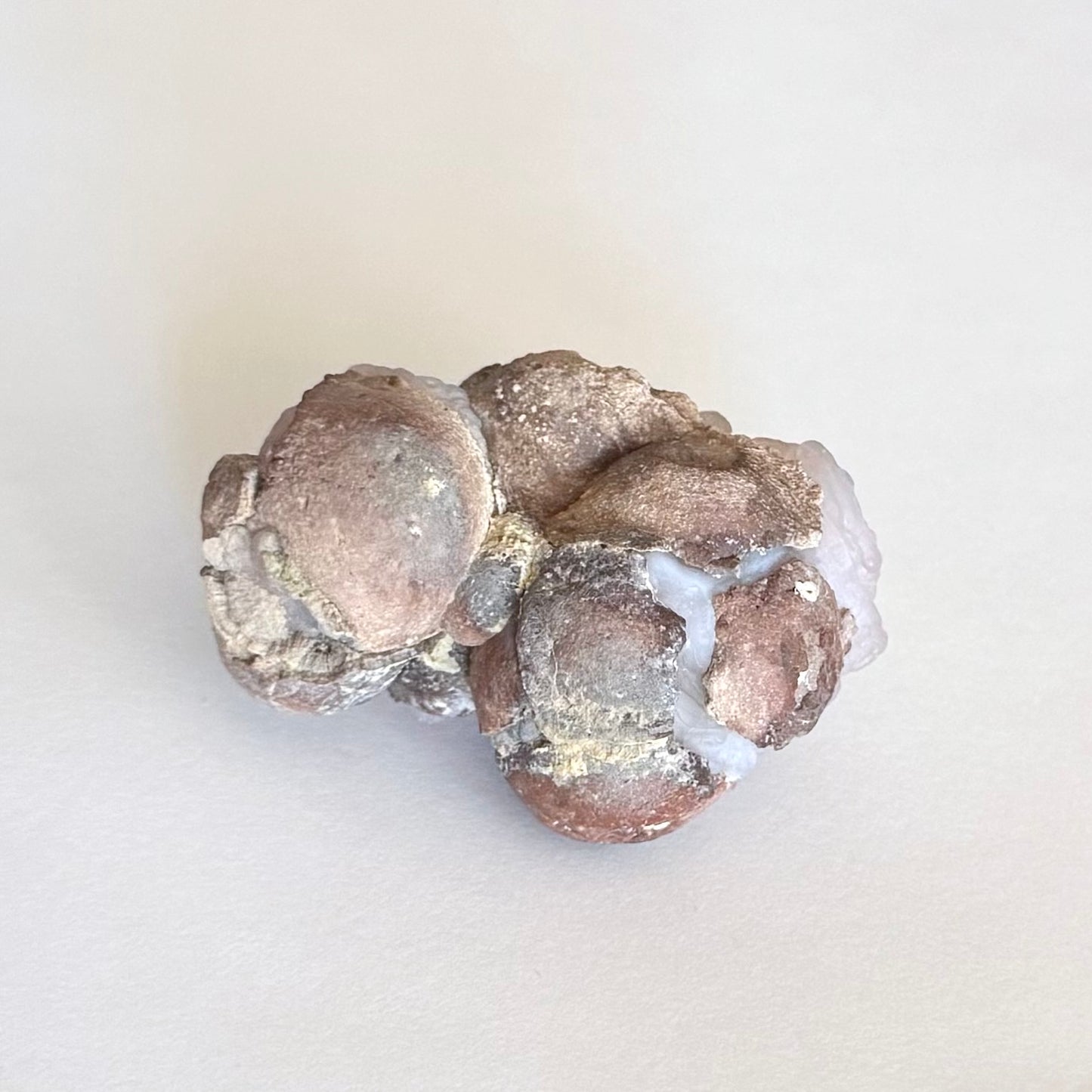 The backside of the piece, several egg-shaped forms of red-brown rock matrix, crackled with the light chalcedony visible through the cracks.