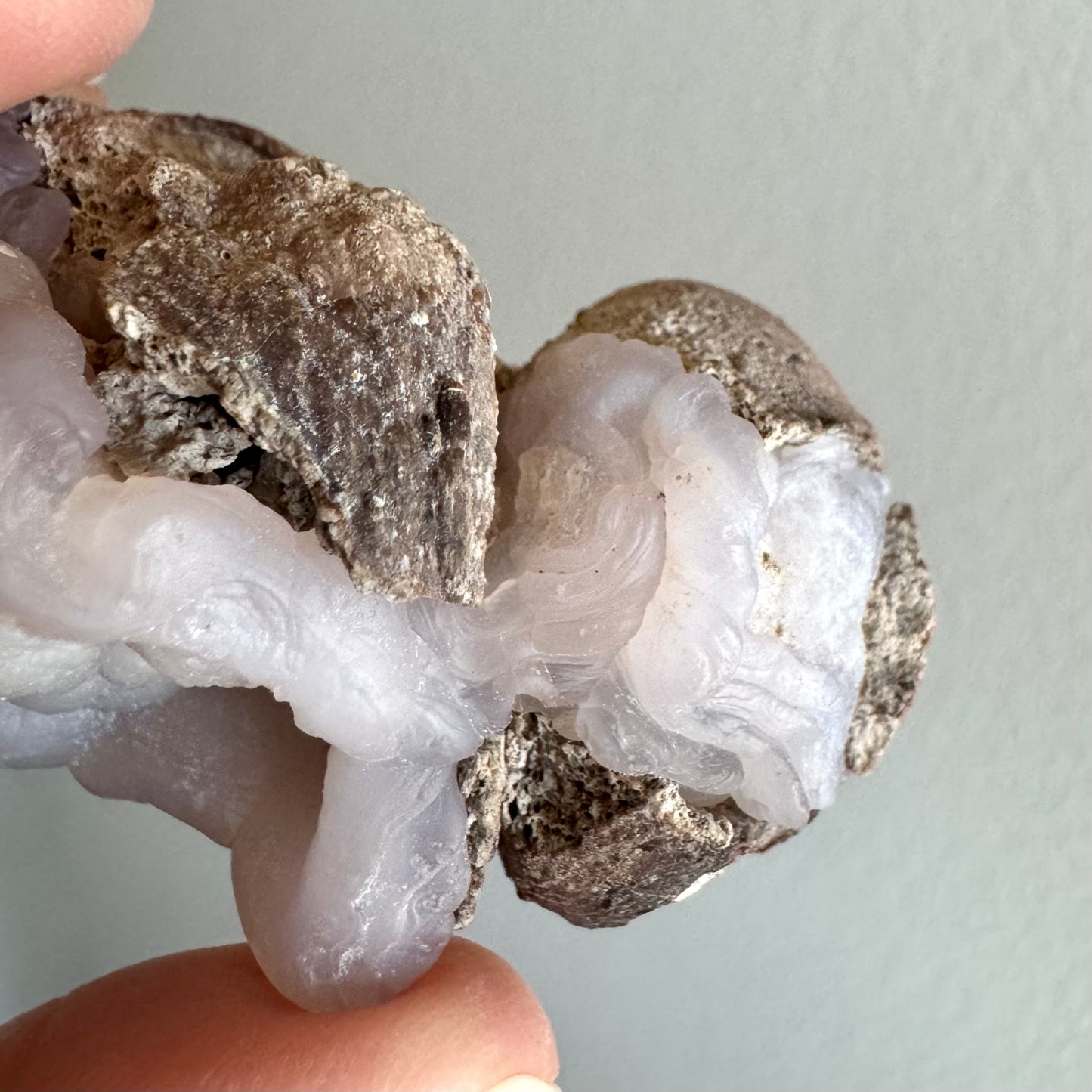 Detail of the third, smallest nodule in the formation, an egg-shaped piece with no opening or hollow interior. Instead, the surface is partially covered with matrix, and partially twisted ropy patterns.