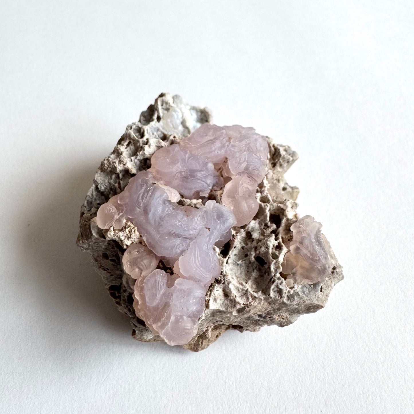 Angled view of the piece, showing more undulating and snaking chalcedony with ropy texture and bulbous forms that appear as if dripping over the edge.