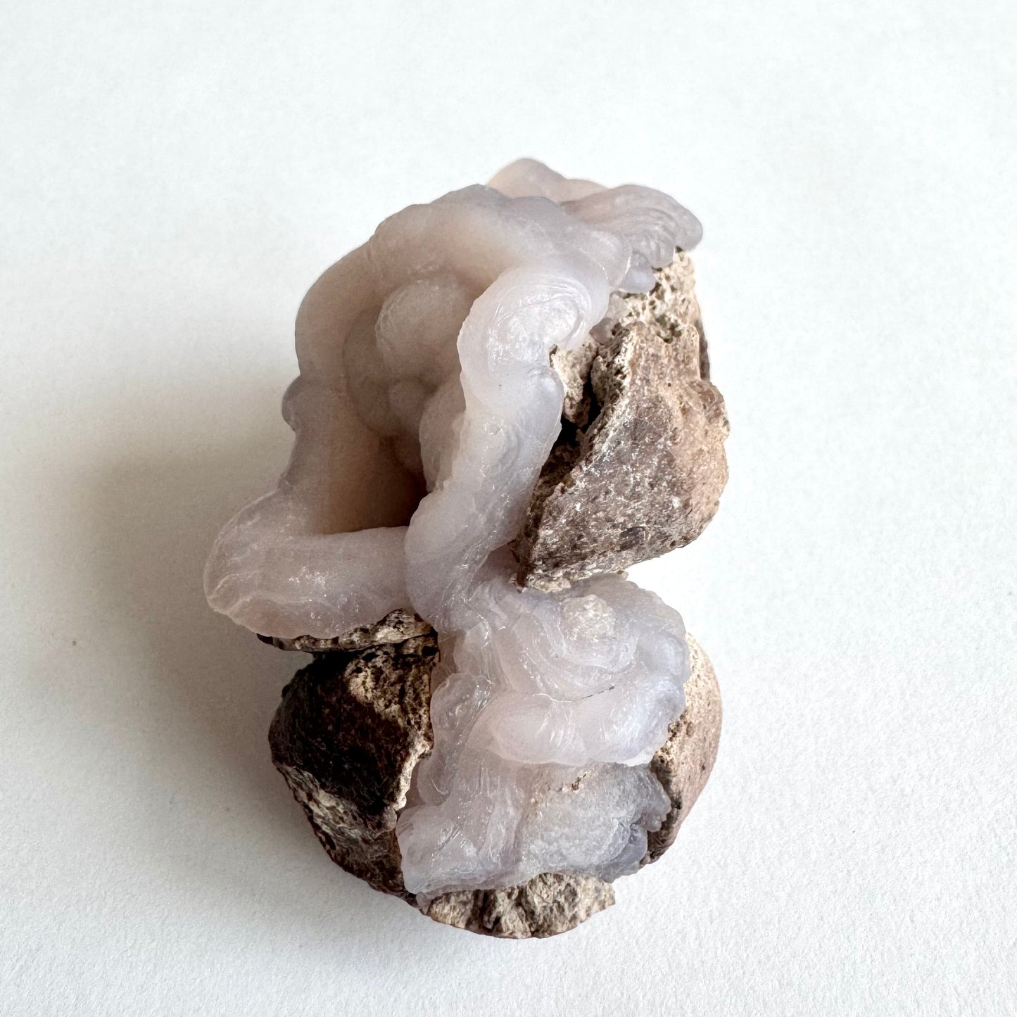 Another side-view of the piece, tilted with the openings pointed to the left. This reveals the third nodule is not mostly covered with matrix, but has a large patch of concentric, lumpy, twisting banding.