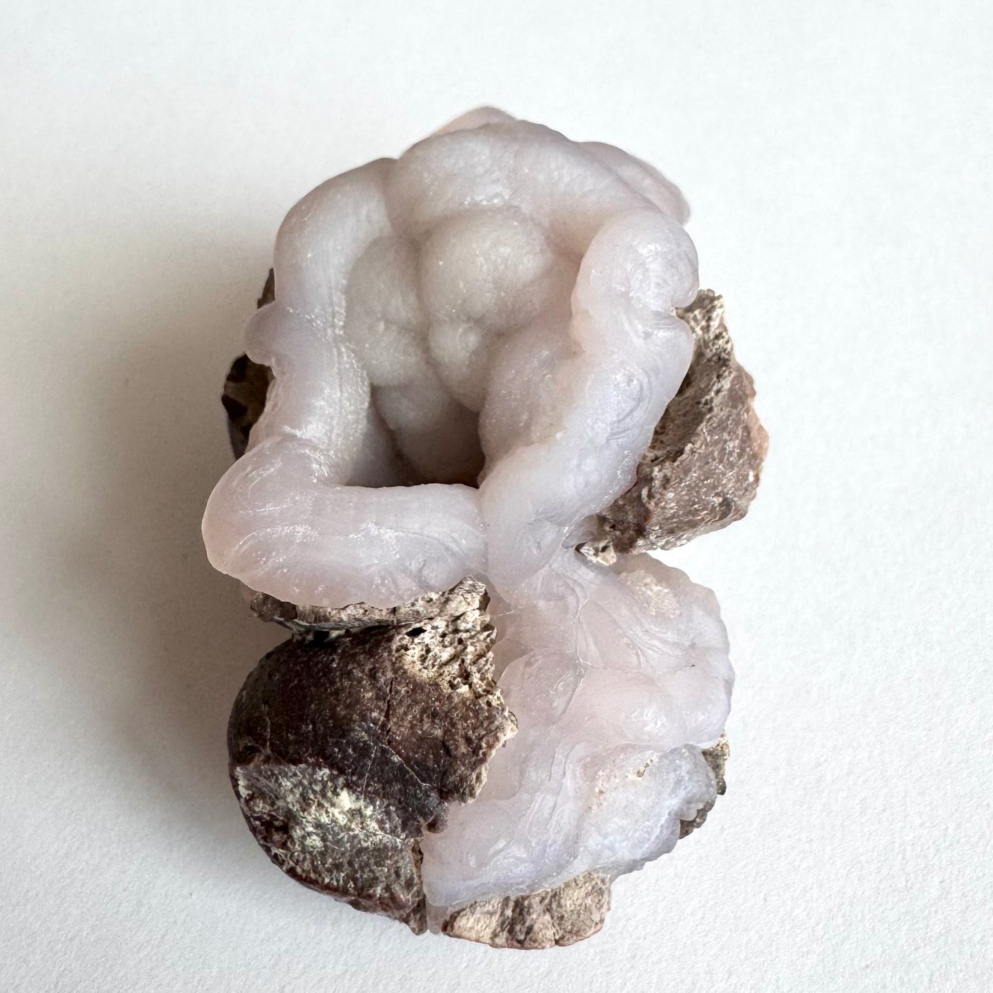 Detail of the larger open nodule, with excellent form. Thick rims with ropy texture also have swirls and botryoidal forms. The smaller nodule is half-covered with matrix, but shows continuation of the ropy pattern from the large piece as if pouring into the smaller one.