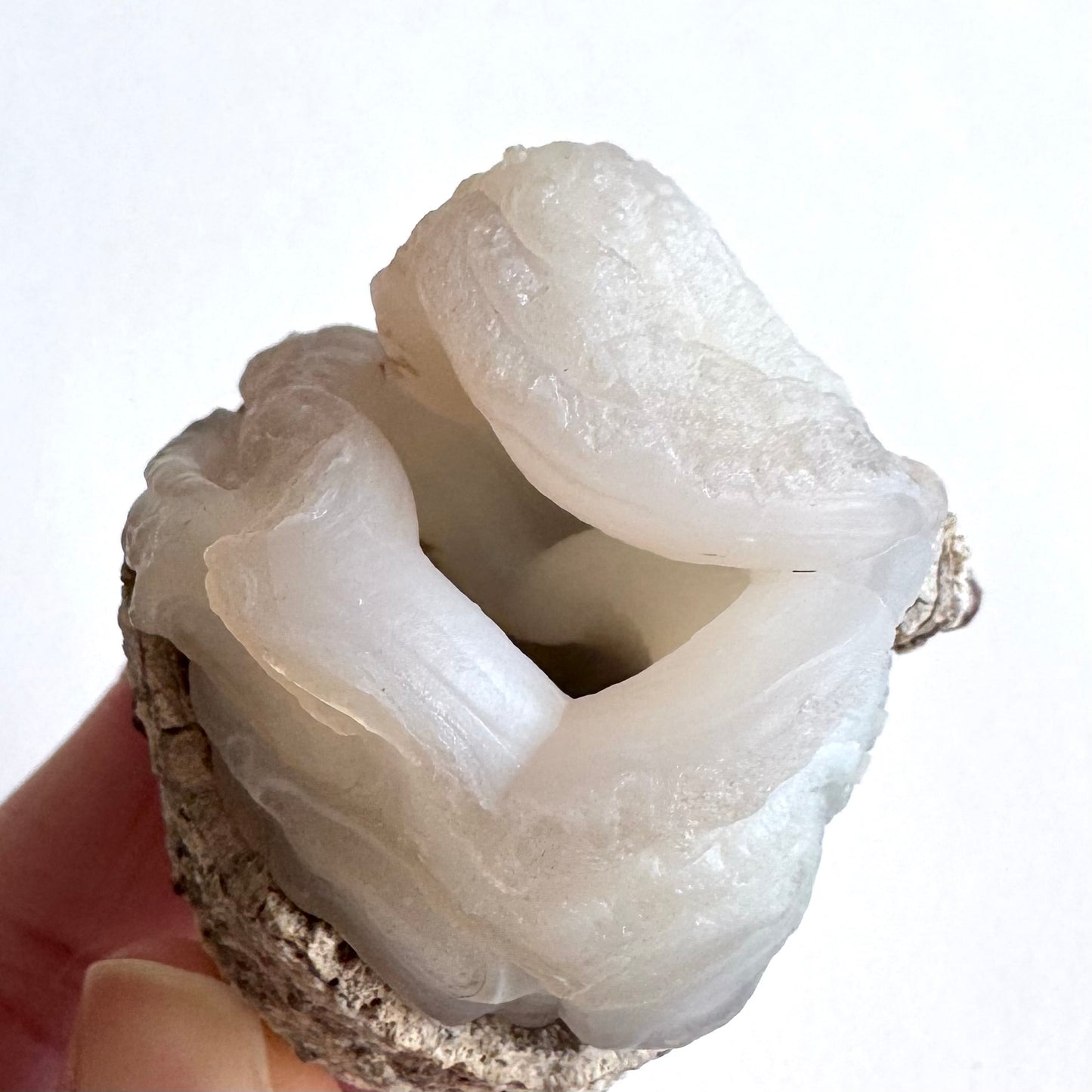 Close detail view into the opening in the nodule, with undulating edges around it and ropy botryoidal forms.