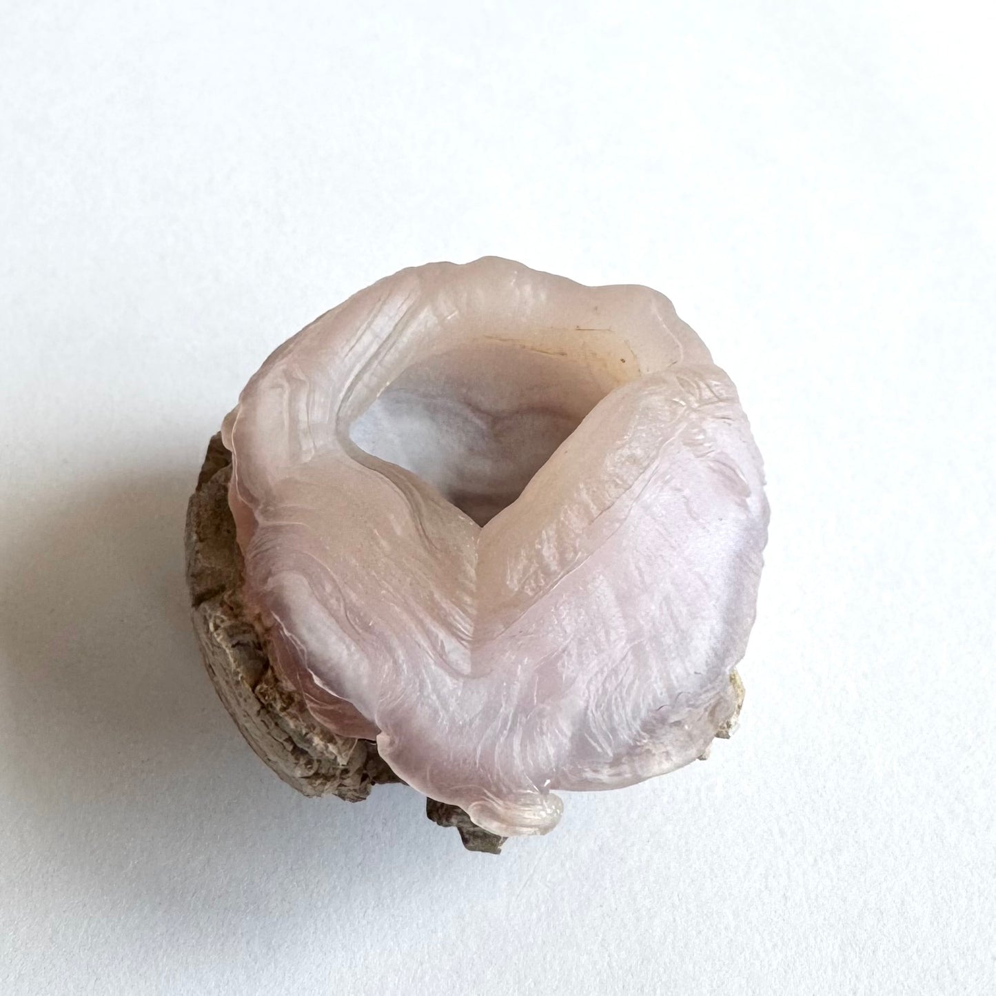 Side-view of the piece, with the ropy banding appearing as if melting, with flesh-like knobs and wrinkling on the surface. The banding around the opening undulates.