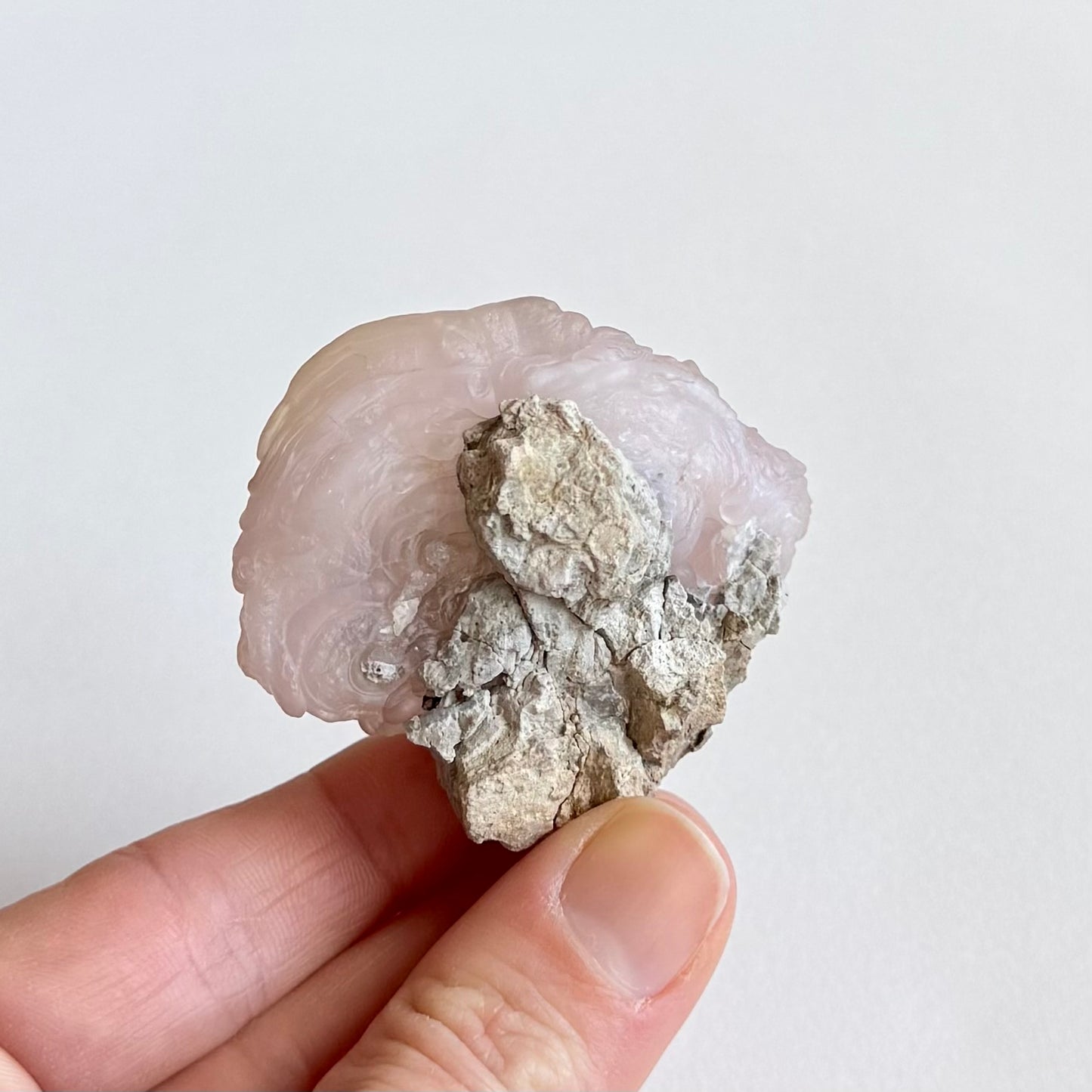 The back of the piece, some botryoidal forms and banding visible, partially covered with a light gray matrix.