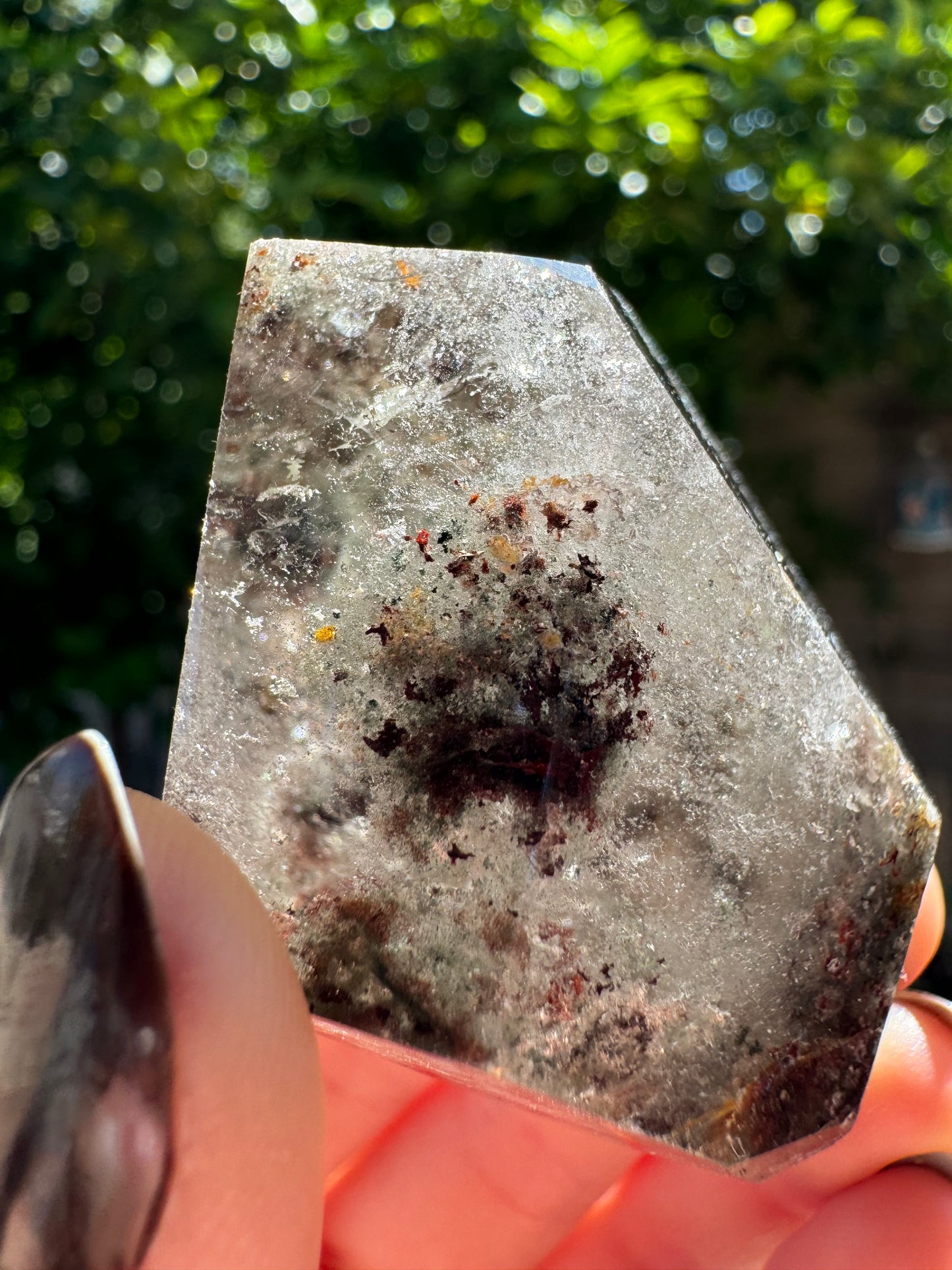Detail view of a face that has a dark spherical formation that looks roughly spiky like covid, surrounded by wispy inclusions.