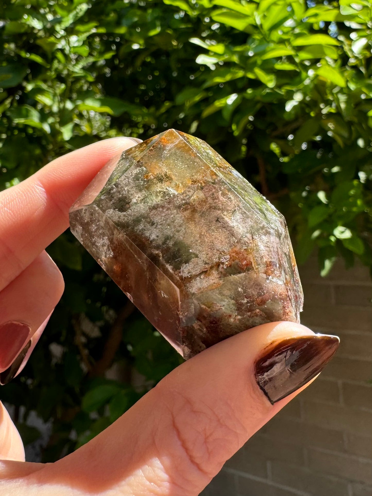 Angled view of the dark side of the piece, near-opaque with inclusions. The front is covered in lumpy light chlorite with a slightly purple hue.