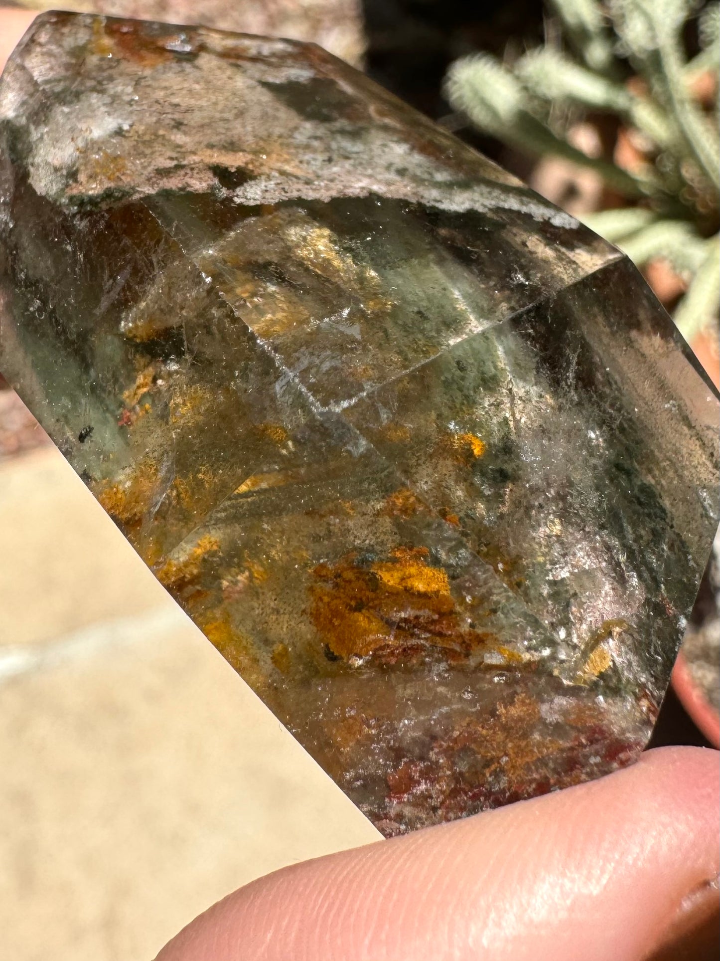 Close view of a corner with abraded edges, inside are fine parallel bands of green spots near a large orange inclusion