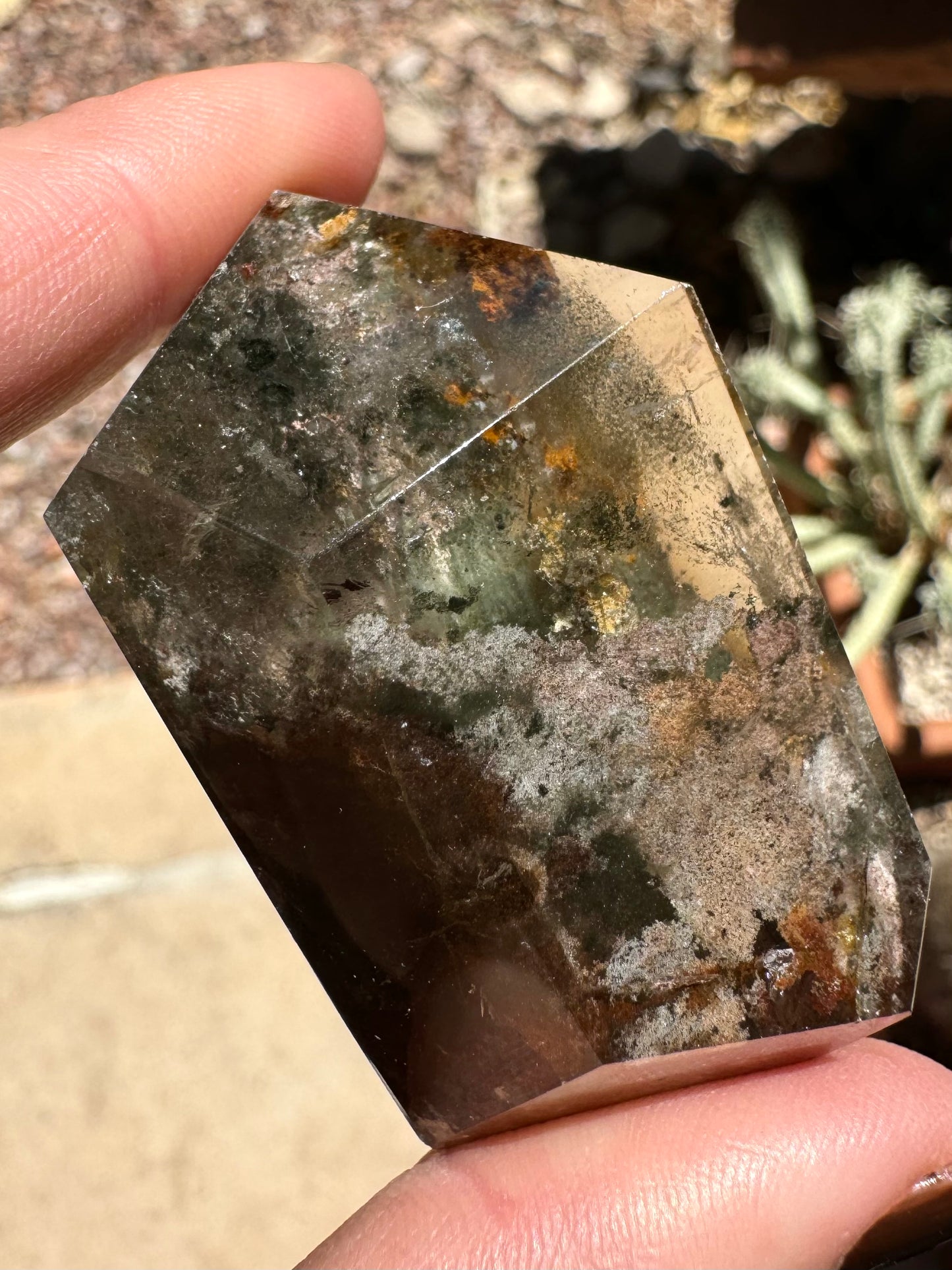 Closer view of the piece with sunlight on the surface, with inclusions looking darker and less colorful than when side-lit.