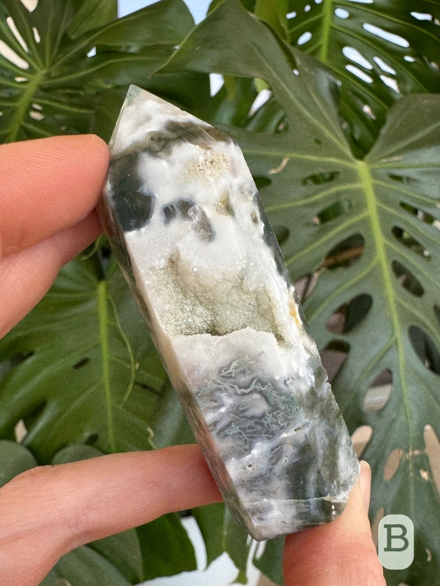 Option B, a six-sided opaque white moss agate tower with translucent areas with moss green inclusions snaking through them. There is a cavity in the center.