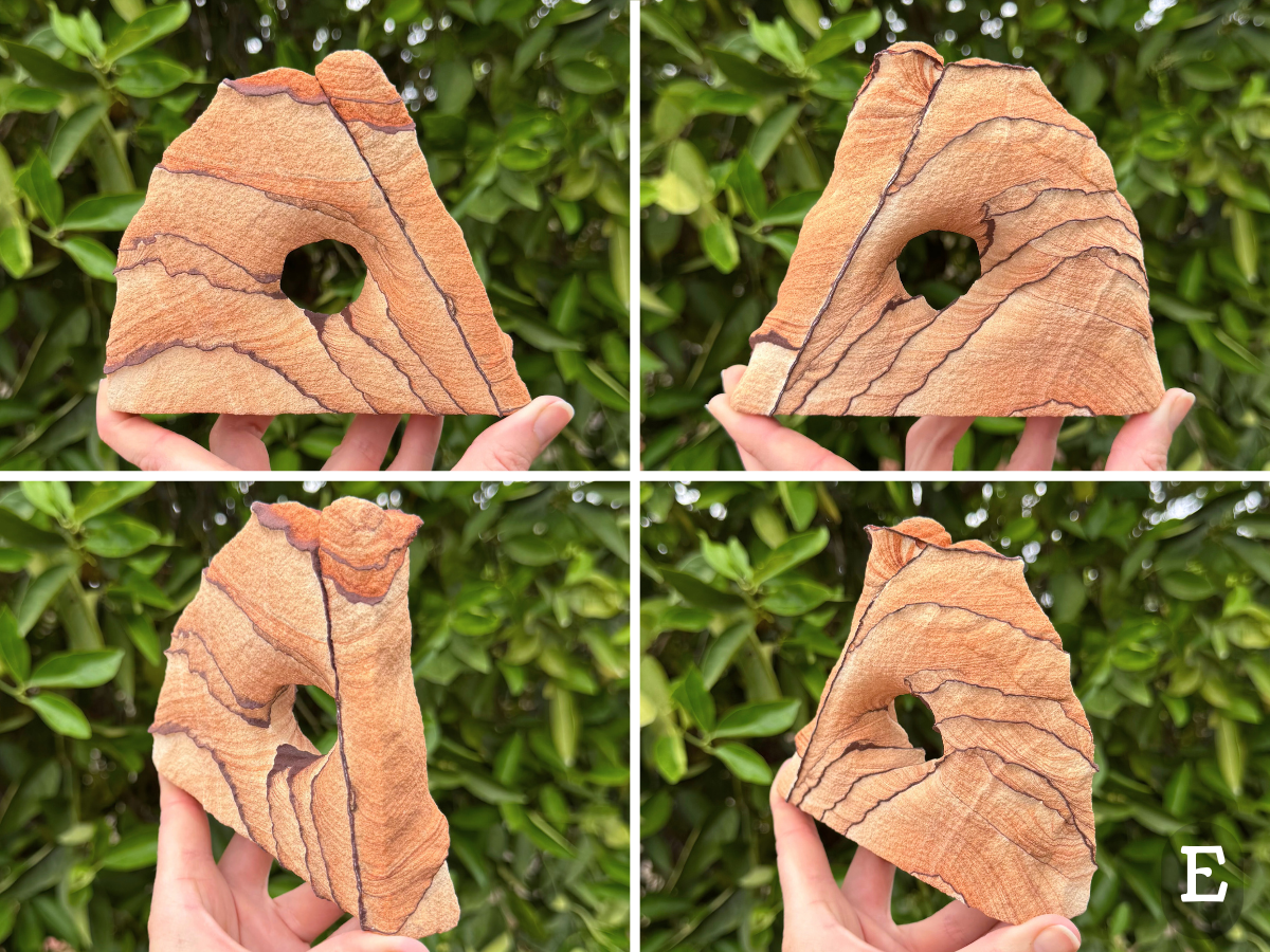 Option E, a wide sandstone arch, flat and angled on one edge, and rounded on the other. One thin dark iron band runs parallel to the length of the straight edge. The piece has light orange pattern, with subtle layers curving between thin dark iron bands that curve across the main faces. The very top has more saturated orange color.