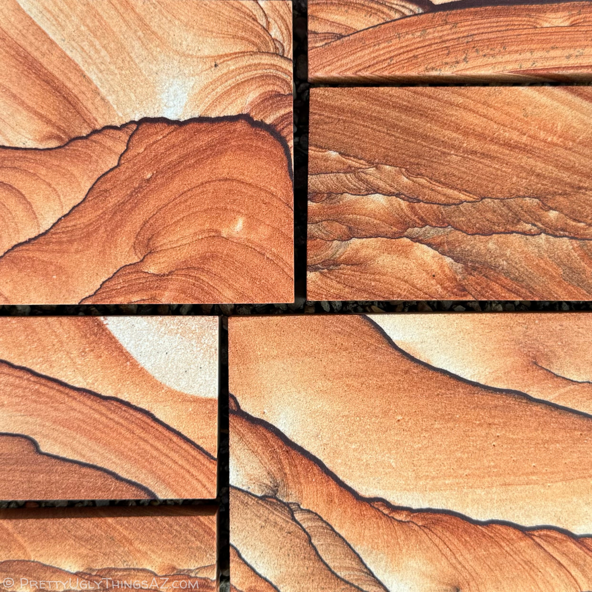 Several small and medium-sized pieces of picture sandstone cut into rectangular slabs, arranged closely like tiles in a mosaic on a dark background. The sandstone is a vibrant red-orange color, with pieces showing variation in patterns. Some has dark iron bands, some parallel layers, others curved layers and scallop patterns.