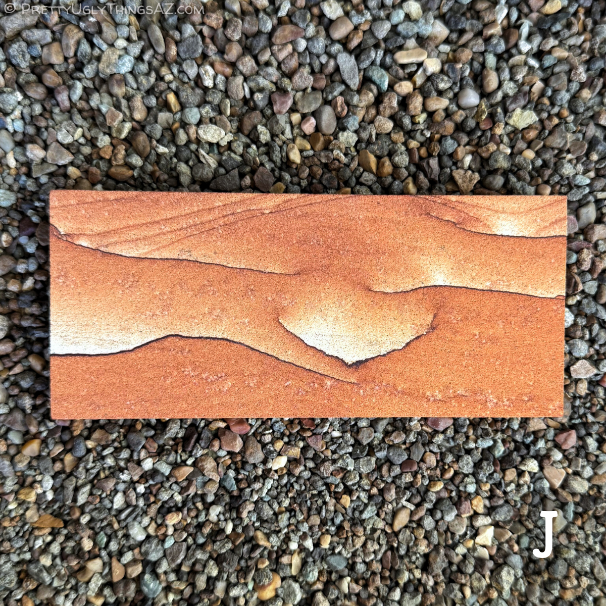 Option J, a long rectangular piece with simple pattern, that is mostly a red-orange color without layering. The color fades to near-white along one edge of several thin dark iron bands that snake across the surface.