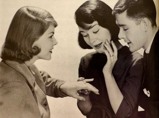 A vintage image of a woman showing a couple her new engagement ring, the other woman adoring it