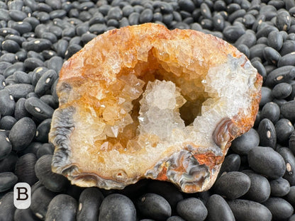 Option B: the other half of the geode with the top half stained orange and the bottom half colorless, with a druzy-covered protrusion in the center. The druzy has large crystals.