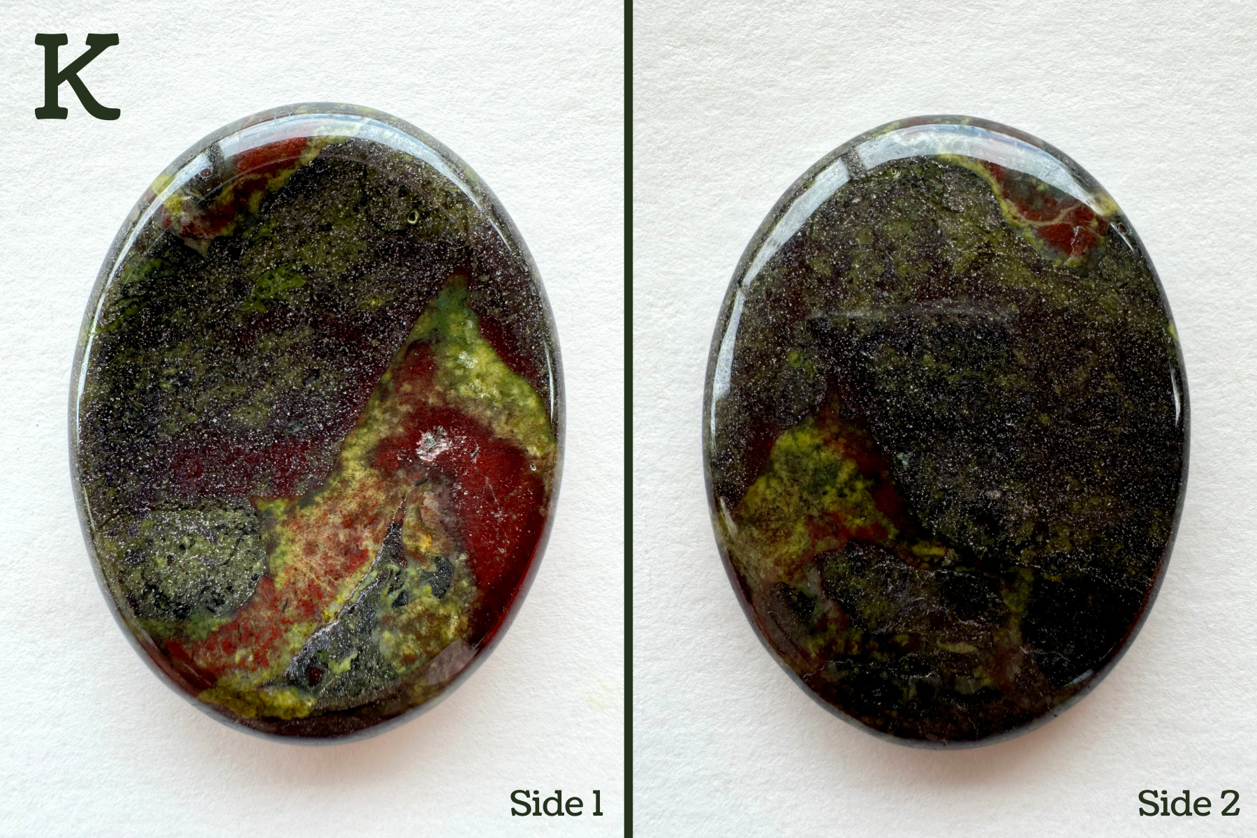 Option K, a dark olive-gray grainy base color with wispy green and red coloration in it. The inverted side has bold deep red and lime green patches in it, less visible on the back. There is a pock mark in the red patch.