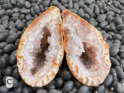 Option C: a tear-drop shaped geode lined with chunky colorless druzy, which turns to white at the edges and has swirling feathery patterns in light brown.