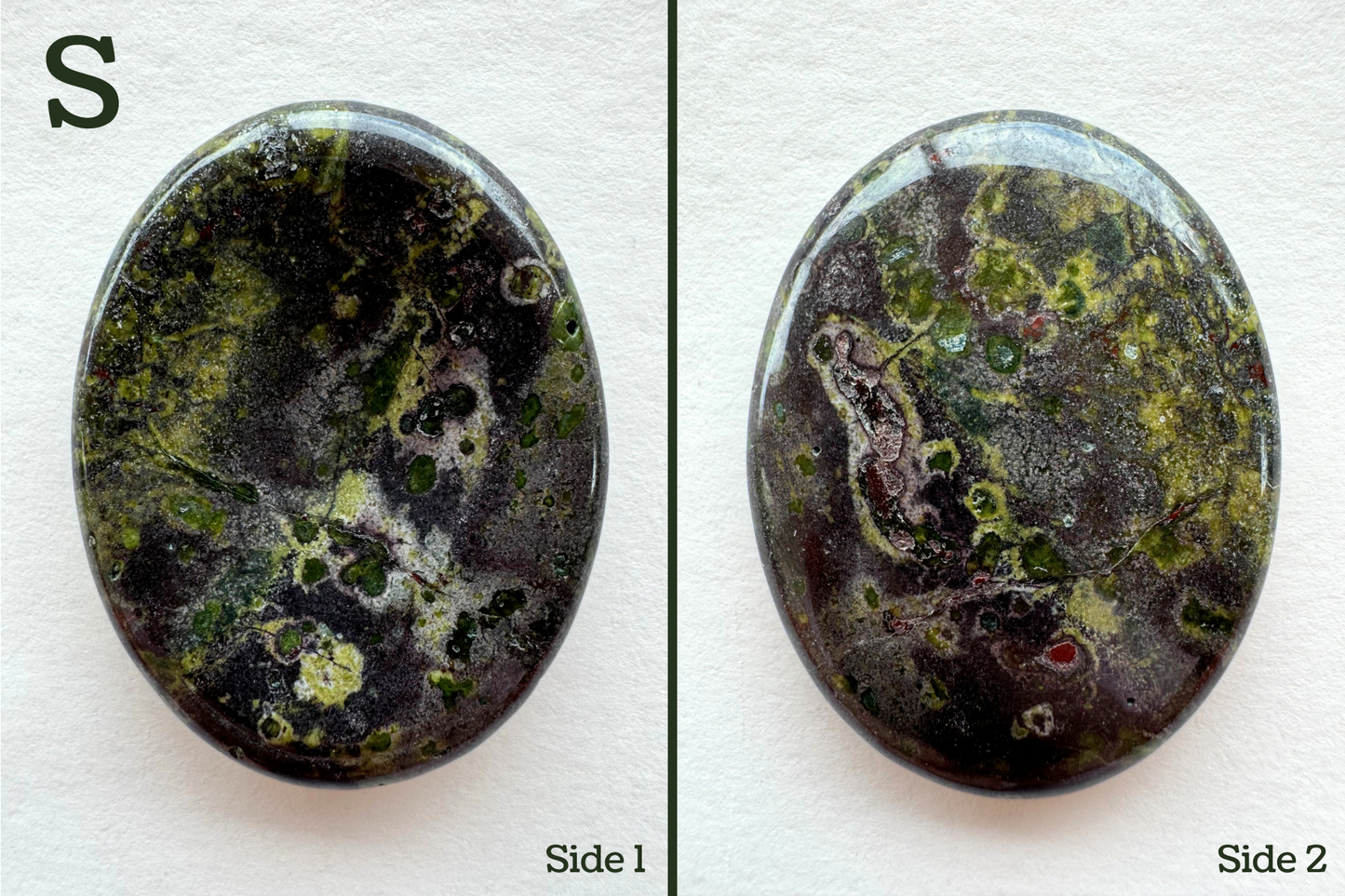 Option S, a grainy dark reddish gray base color with several colorful crystals embedded in it and seen in cross-section, with saturated green and blue green color and a ring of light lime around them. Some pocking on the back.