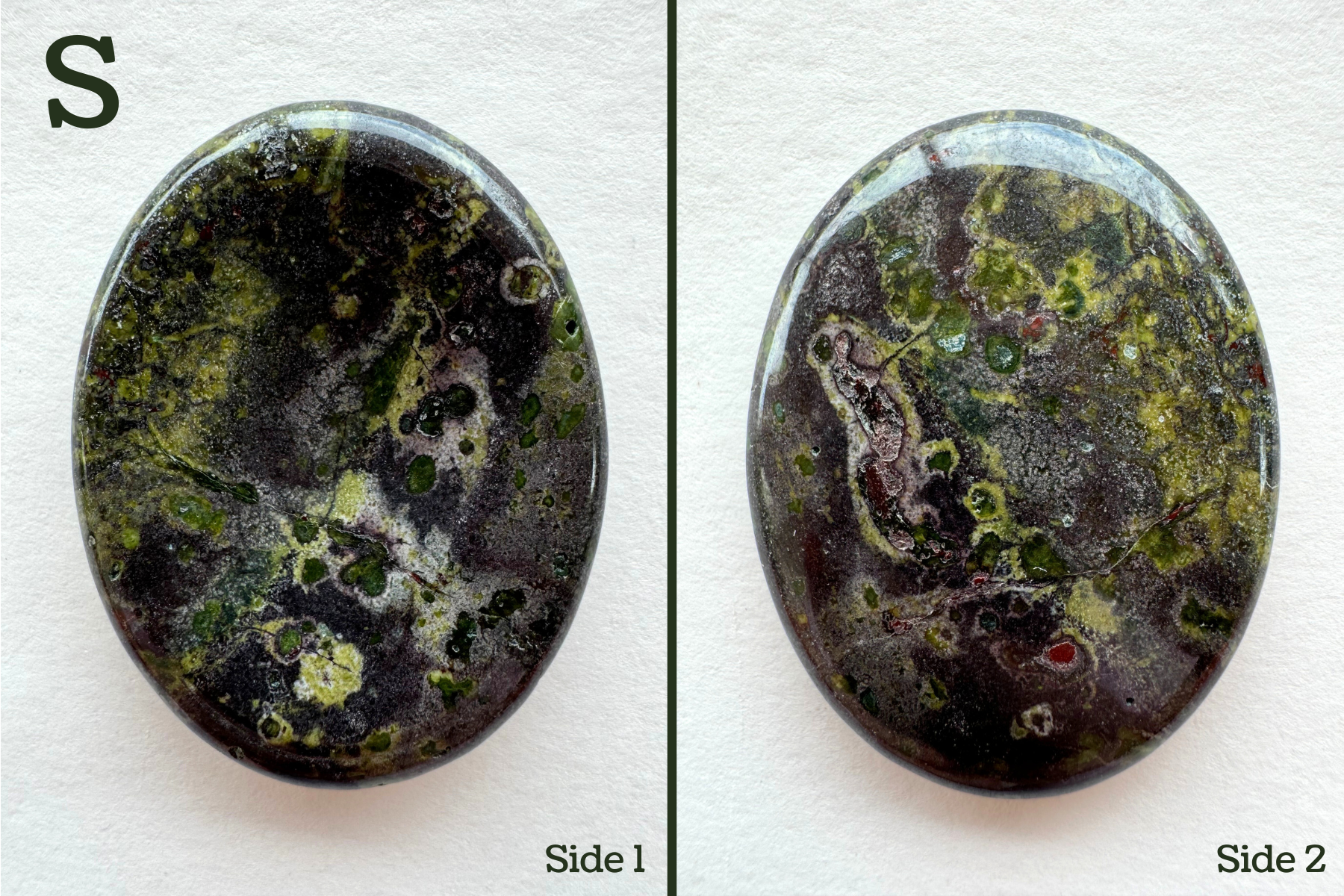 Option S, a grainy dark reddish gray base color with several colorful crystals embedded in it and seen in cross-section, with saturated green and blue green color and a ring of light lime around them. Some pocking on the back.