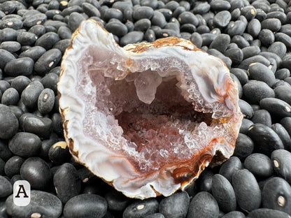 Option A: Detail of one half of the geode, with red coloration showing through the interior druzy and a large quartz crystal hanging from the top.