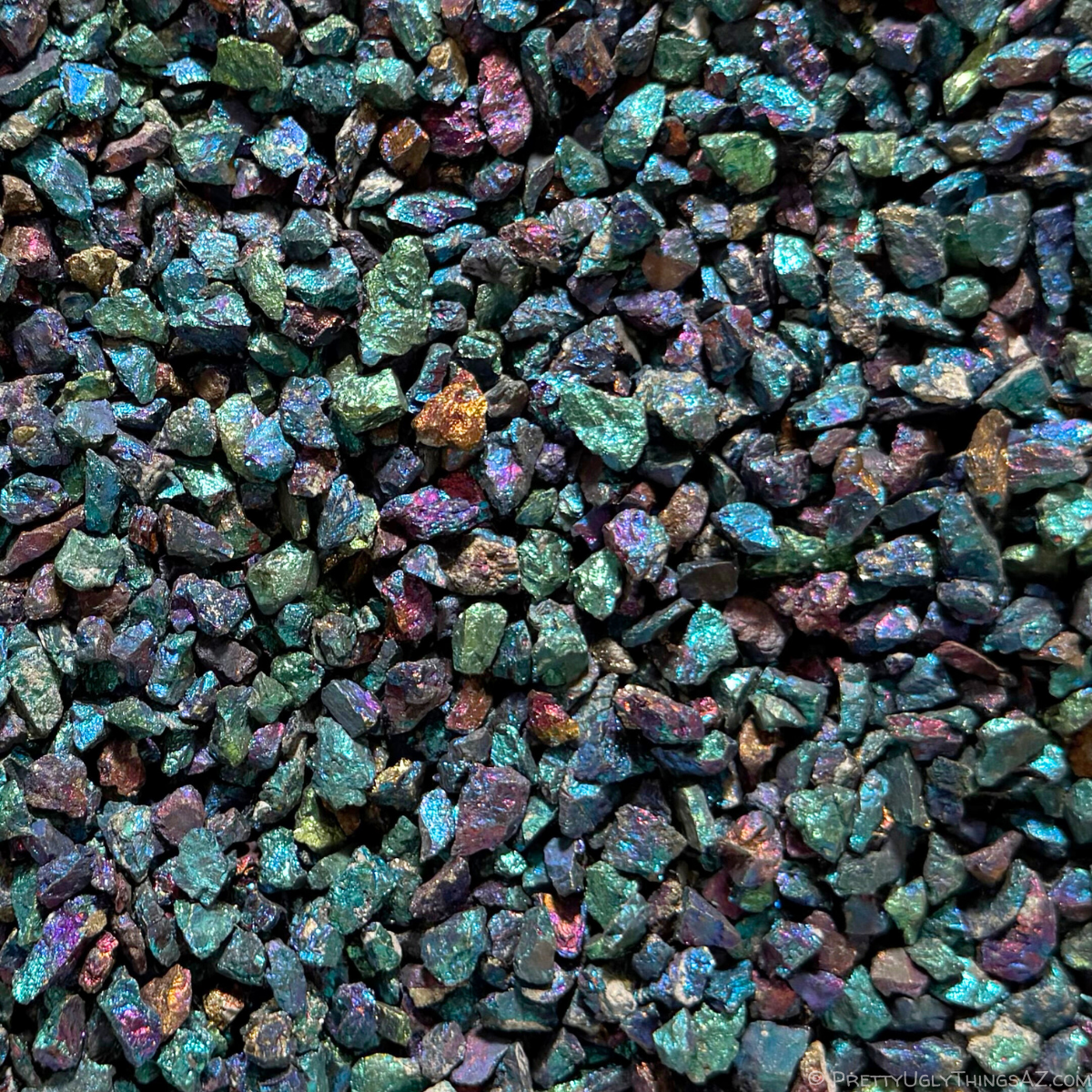 Close view of a bin of the chalcopyrite chips, small irregular pieces with green seeming to be the primary color represented, and blue and purple also common, with a few orange-golden pieces sprinkled in.