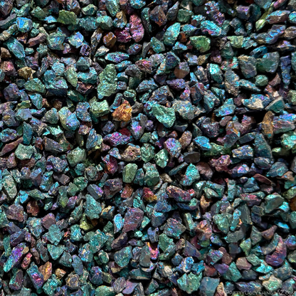 Close view of a bin of the chalcopyrite chips, small irregular pieces with green seeming to be the primary color represented, and blue and purple also common, with a few orange-golden pieces sprinkled in.