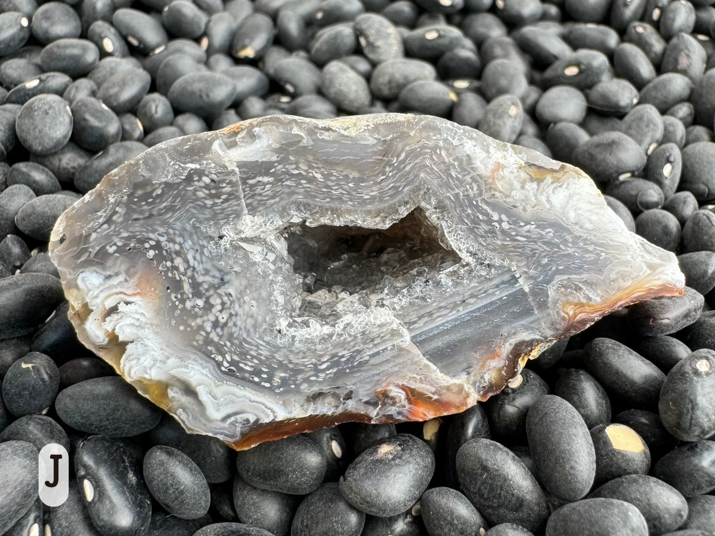 Option J: detail of the other half of the geode, with the spotted pattern turning into white feather-like patterns at the edge. The druzy inside is hard to see due to the depth of the small hollow.