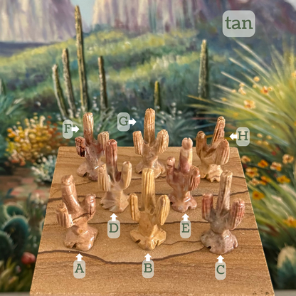 Captioned "tan," eight saguaros labeled A through H. A is a desaturated pink-yellow tan with a dark stripe. B is a smooth butter yellow-tan. C is a grainy light gray with red-pink tinted tips on the branches. D is a smooth tan with a red-tinted top. E is a marbled tan and reddish-tan. F is a warm tan with a dark red patch on one branch. G is a mottled light tan. H is plain tan.