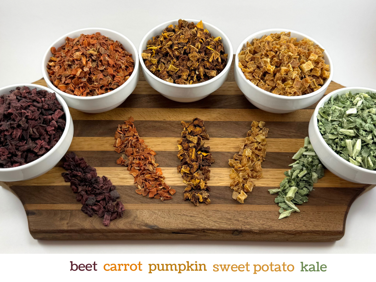 The ingredients in the Fall mix, each in a bowl and spread out on a wood cutting board, and labeled: beet, carrot, pumpkin, sweet potato, kale.