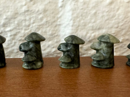 Dark green mushroom trios lined up in a row, showing some variations in natural coloration, with lighter and darker mottling.