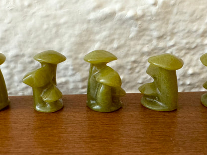 Light yellow green mushroom trios lined up in a row, showing some variations in natural texture.